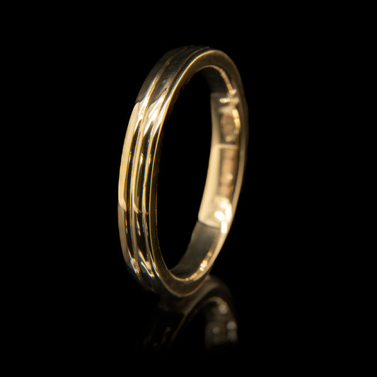 Gold ring with three engraved lines on a black background