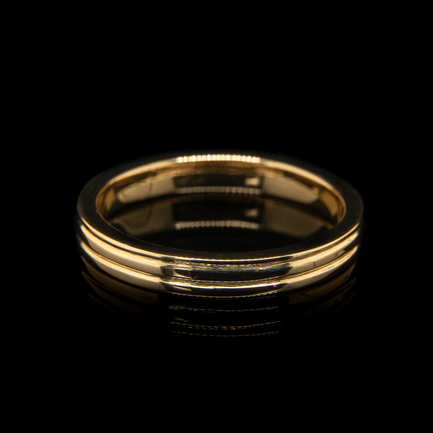 Gold ring with three engraved lines on a black background