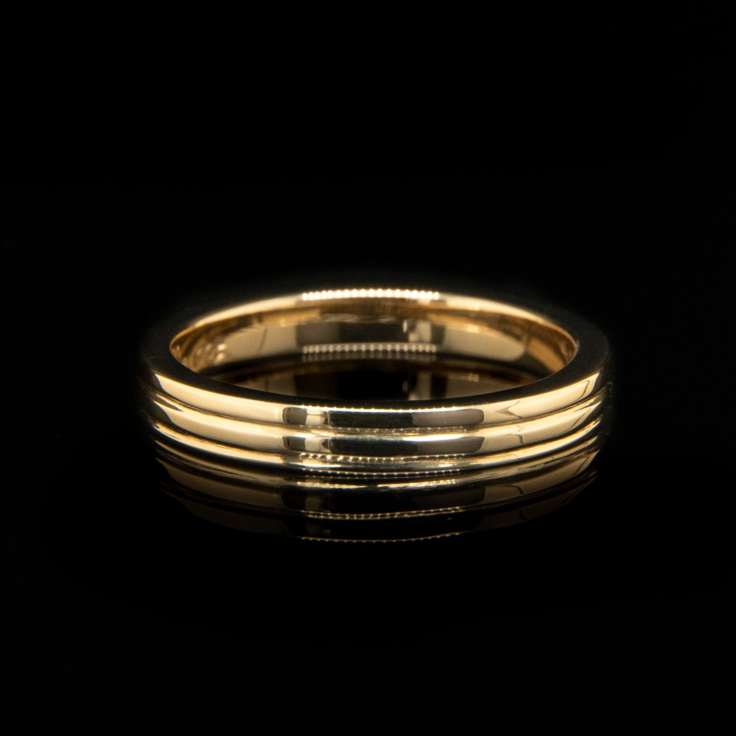 Gold ring with three engraved lines on a black background