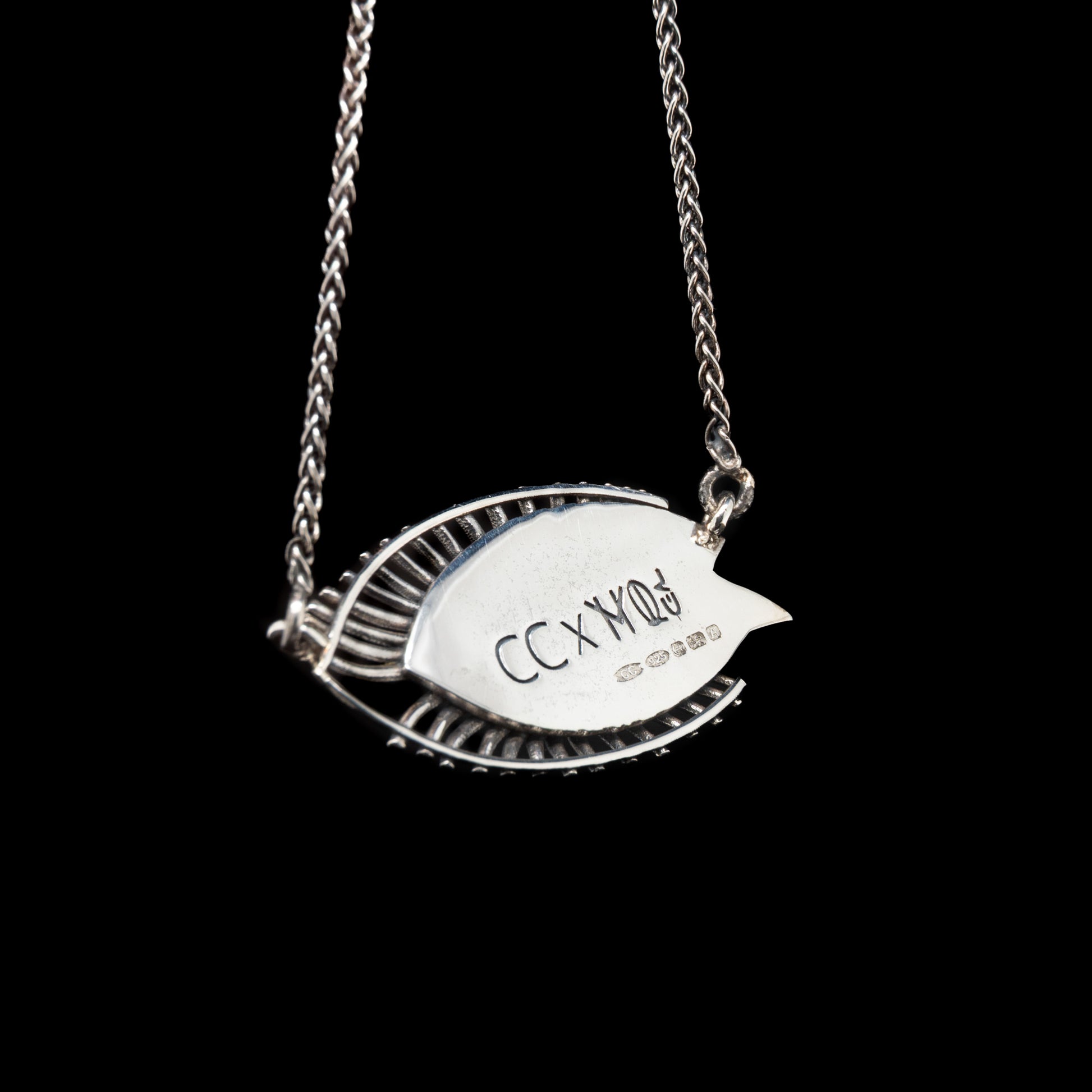 Silver necklace with a leaf-shaped pendant on a black background