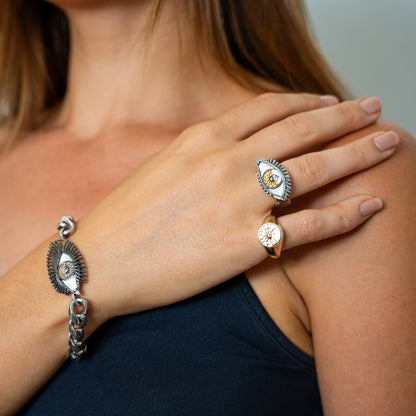 Close-up of a person wearing silver jewelry with intricate designs on a neutral background