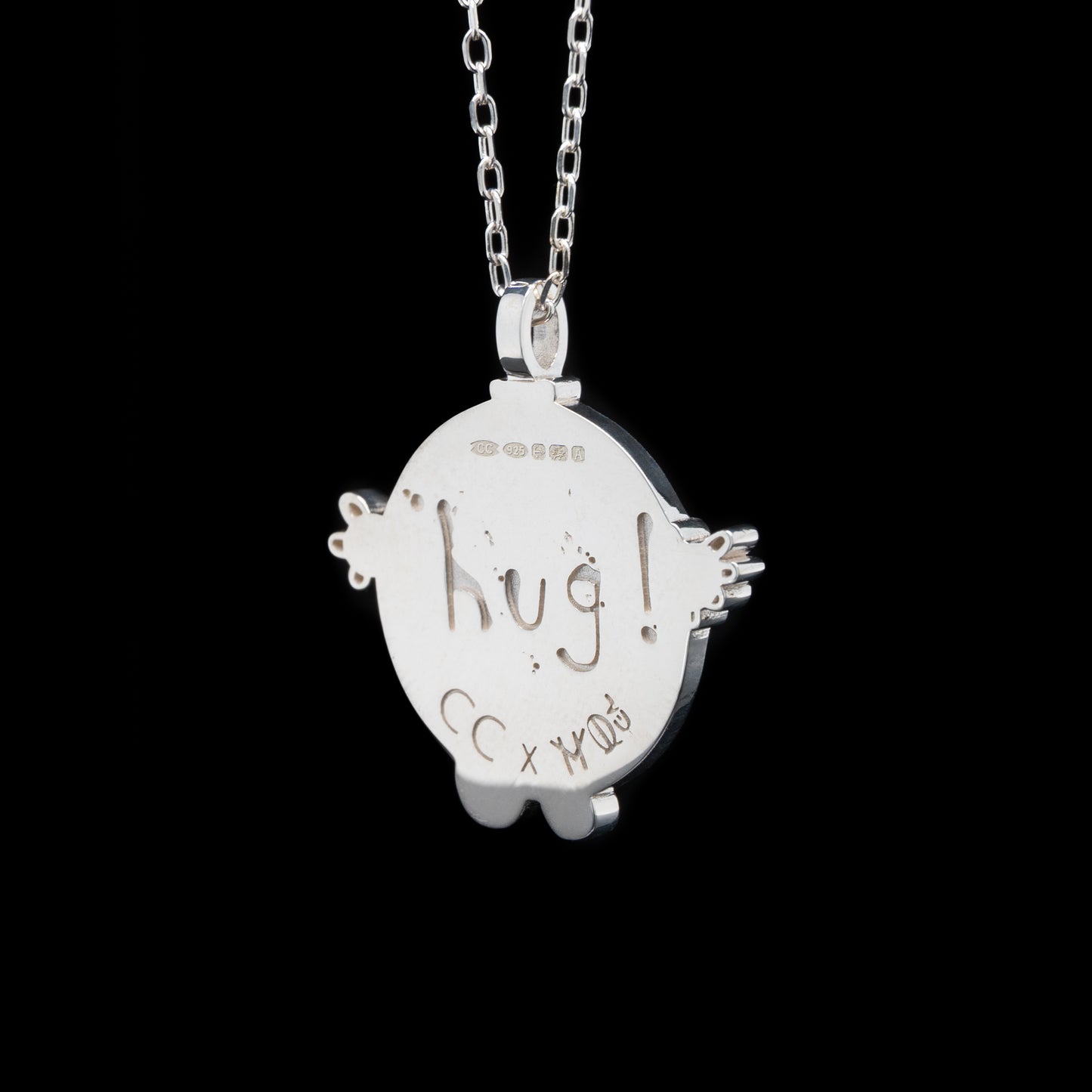 Silver pendant with 'hug!' engraving on a black background