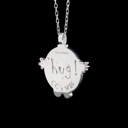 Silver pendant with 'hug!' engraving on a black background