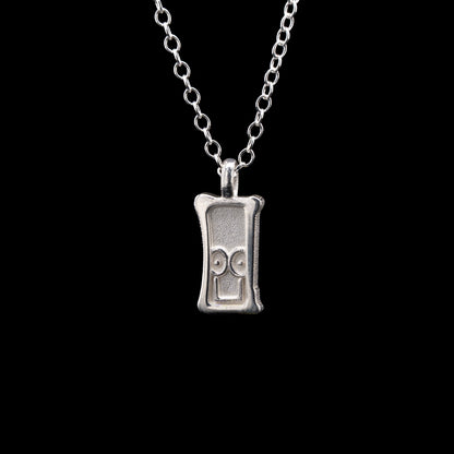 Everyman sterling silver smile head charm pendant necklace on a black background.