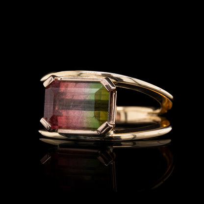 Gold ring with a watermelon tourmaline gemstone on a black background .