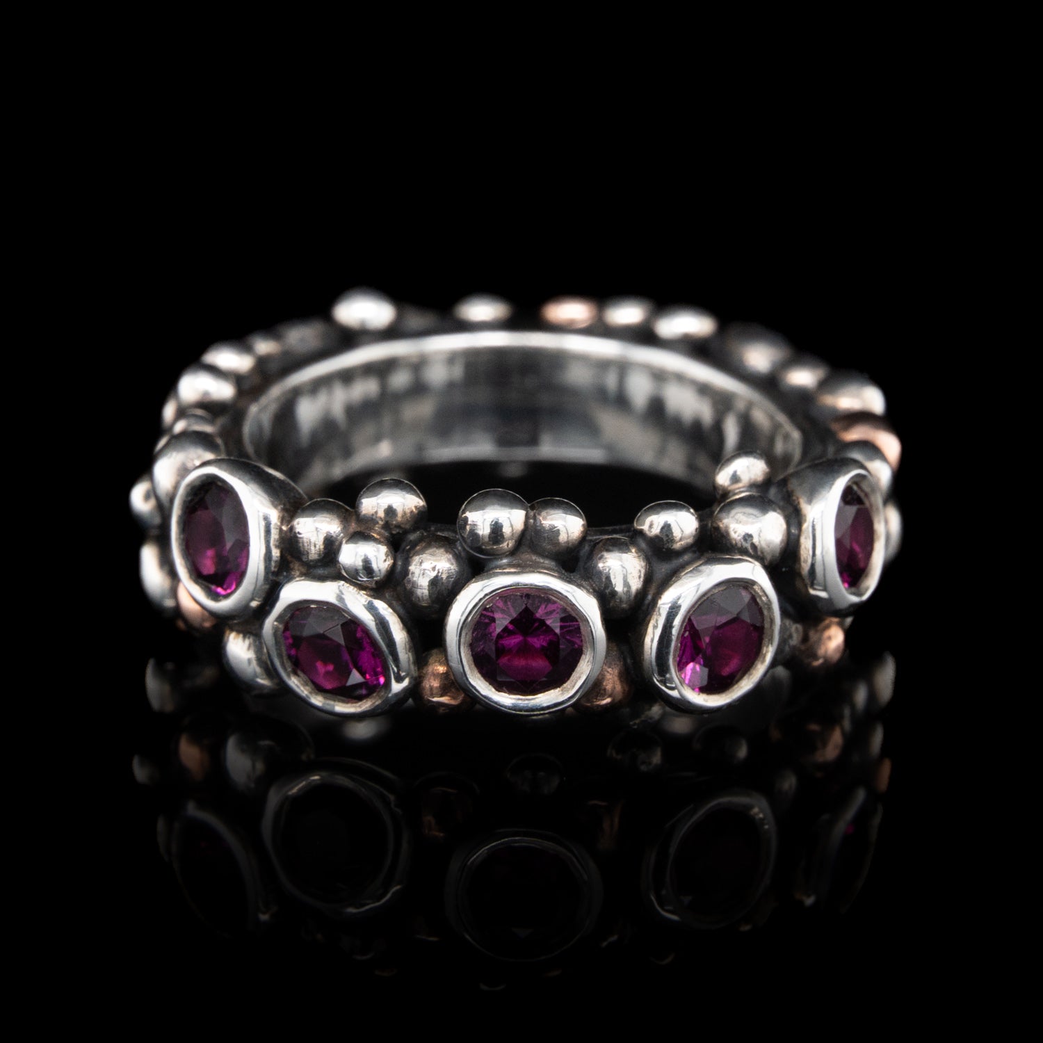 Silver ring with grape garnets gemstones on a black background.