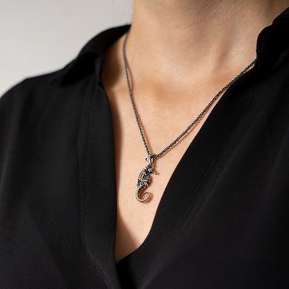 Necklace with a seahorse pendant worn by a person in a black top.